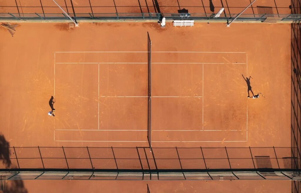 Overhead view of a clay tennis court at Club Med Magna Marbella with two players in a rally